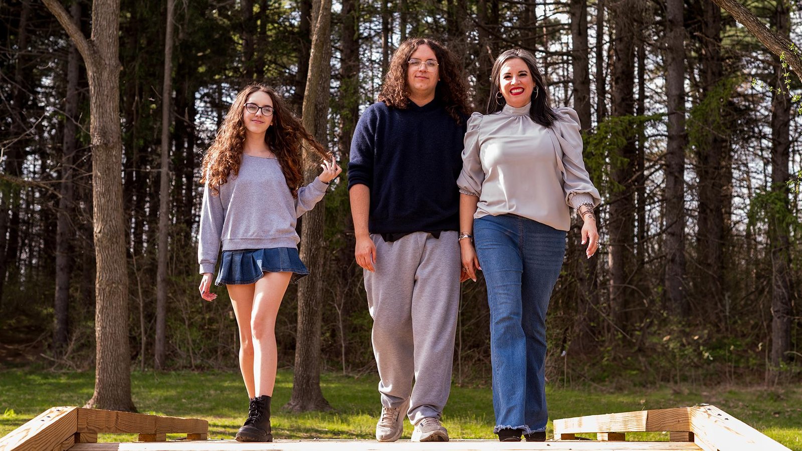 Mom and two teens walking together through the woods during a fall family photo session