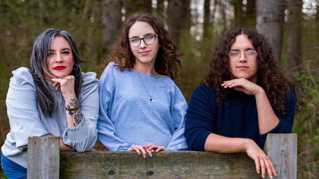 Mom and two teens leaning on a wooden fence for a fall family portrait in Saline, Michigan