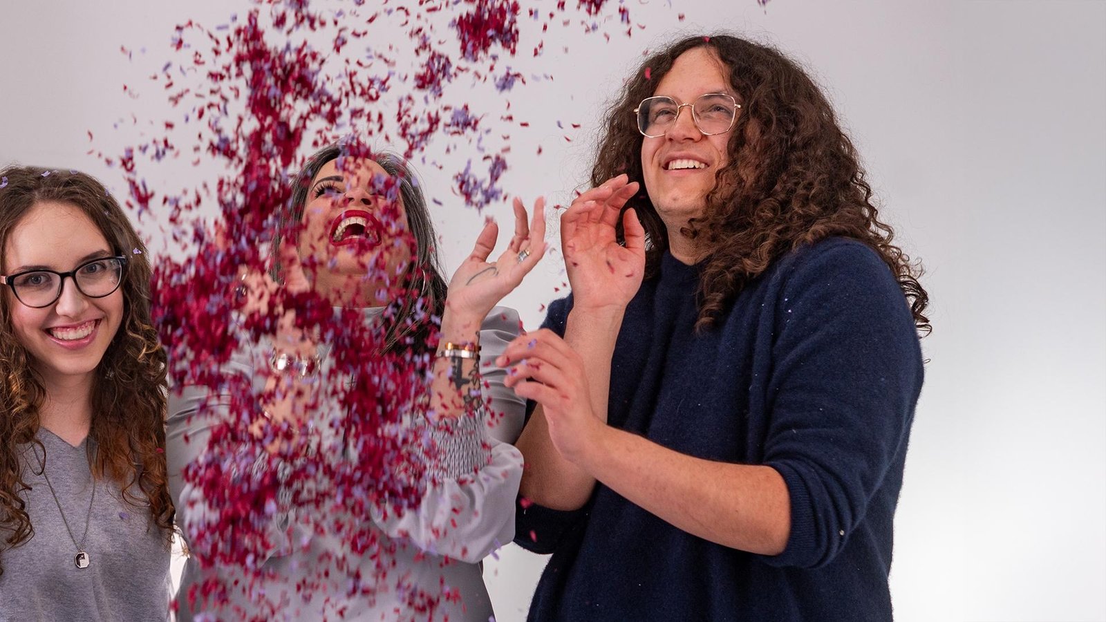 Family laughing as flower petals fly during a playful studio session in Ginger Liemohn Creative’s Saline studio